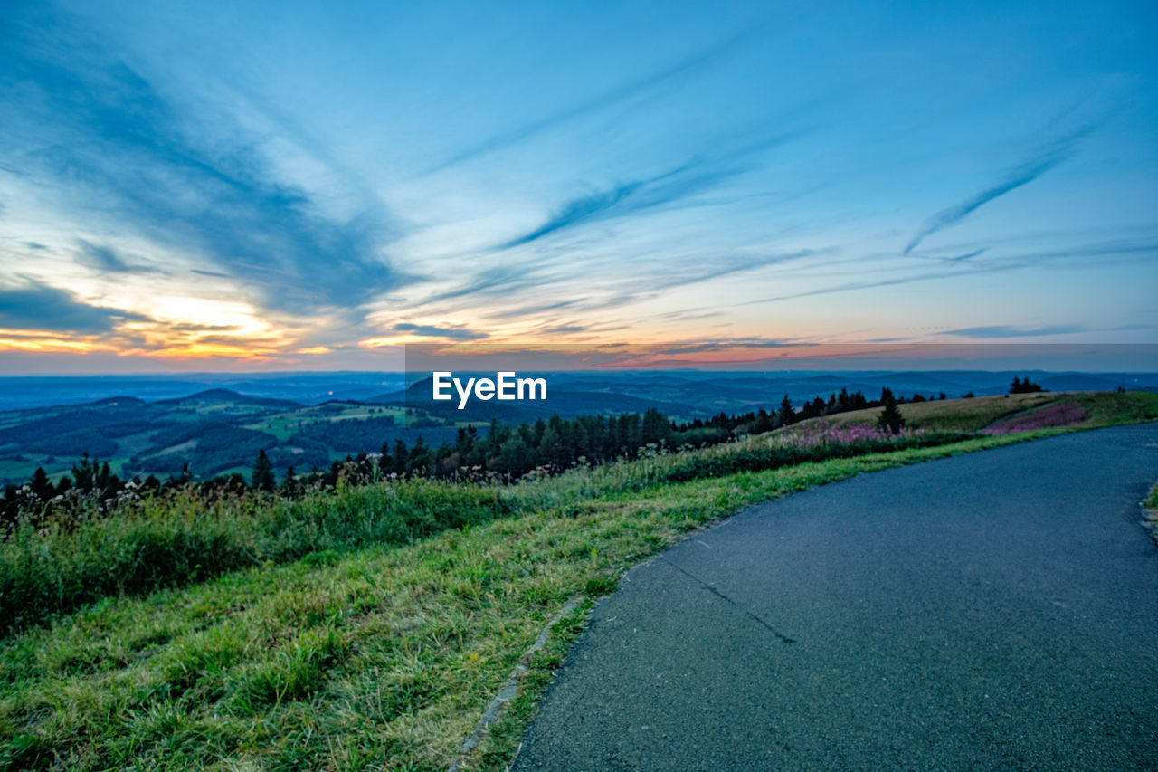 SCENIC VIEW OF ROAD BY LAND AGAINST SKY DURING SUNSET