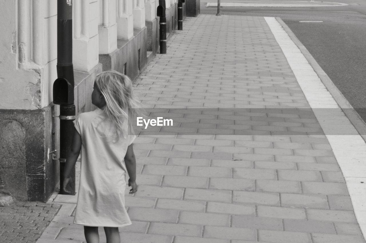 Rear view of girl standing on sidewalk