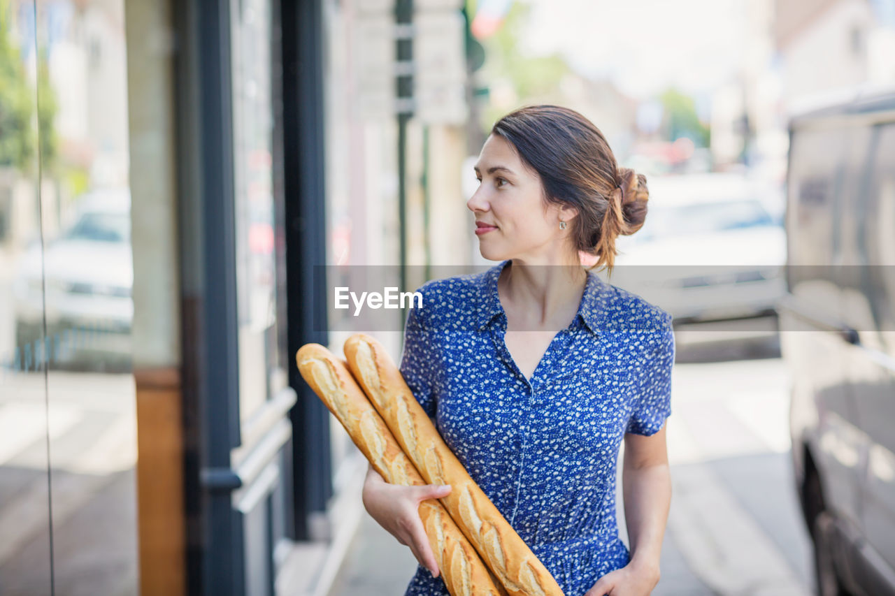 Young woman buying a french baguette