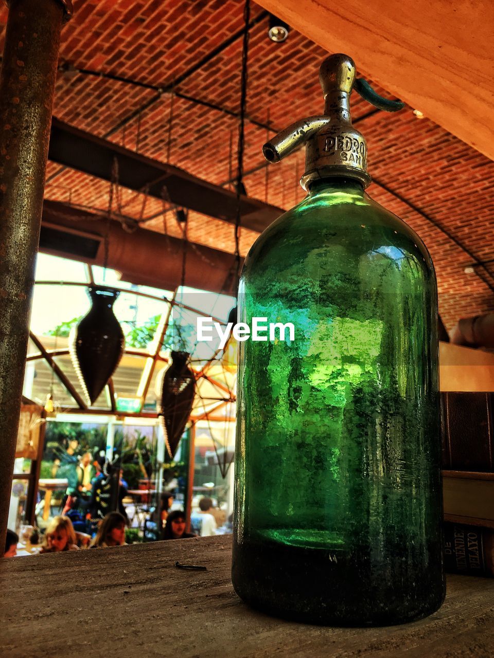 LOW ANGLE VIEW OF ILLUMINATED BOTTLES HANGING IN KITCHEN