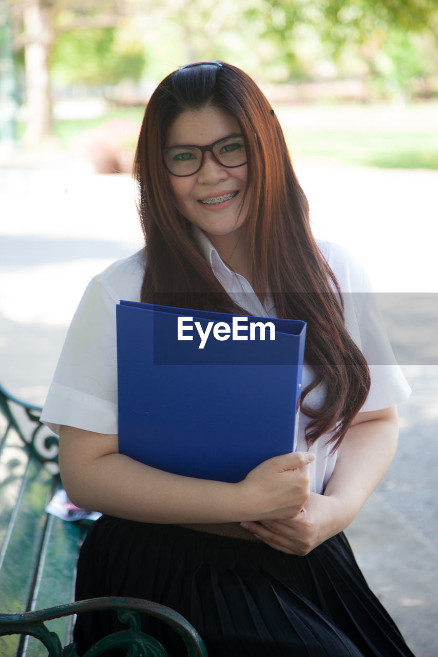 Portrait of young woman holding blue file