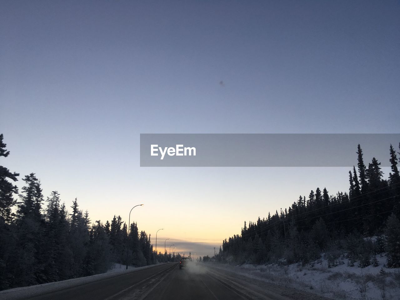 ROAD BY TREES AGAINST SKY DURING SUNSET