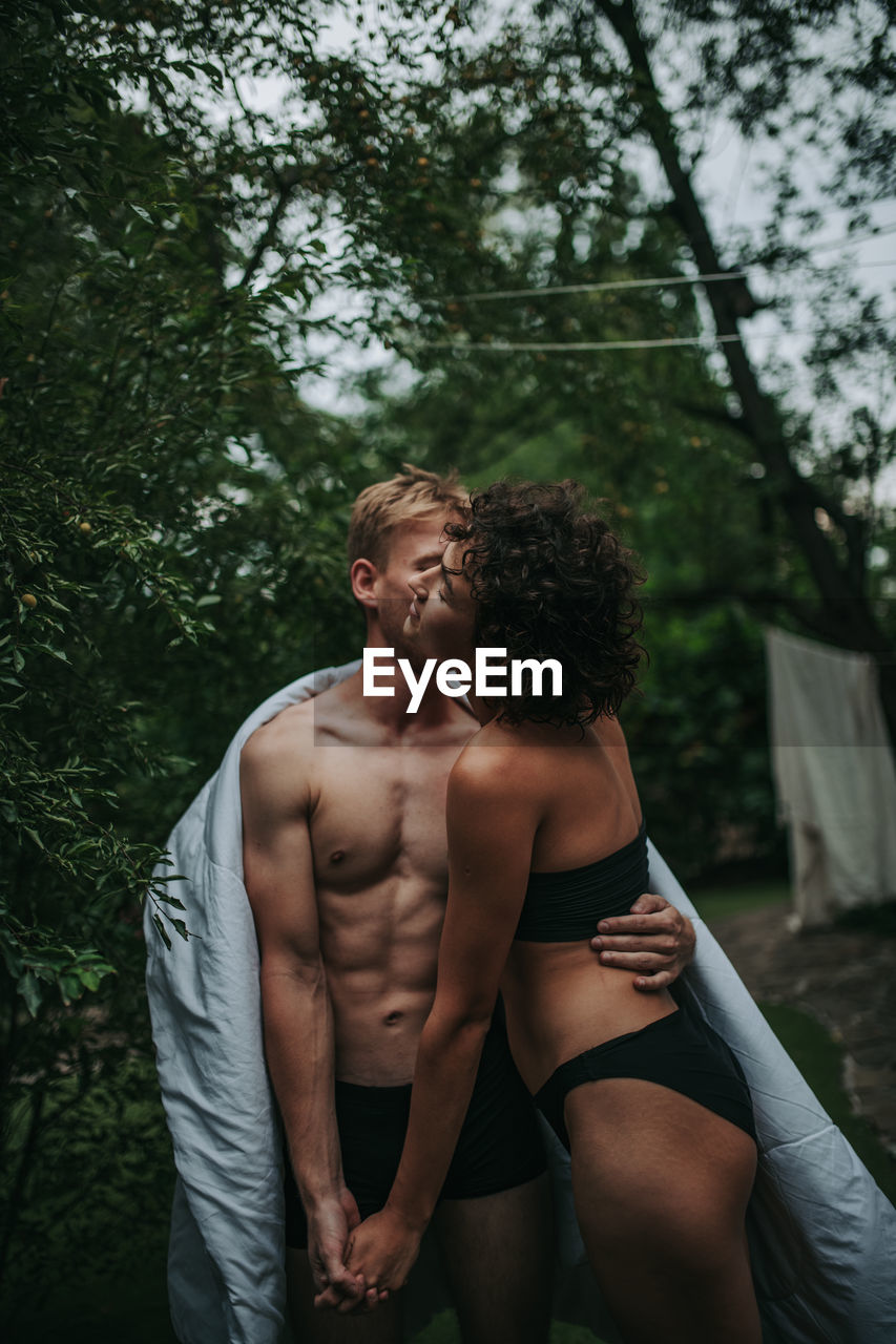 Young couple standing against trees