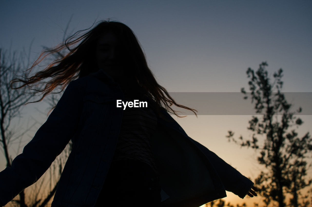 SILHOUETTE WOMAN STANDING AGAINST SKY AT SUNSET