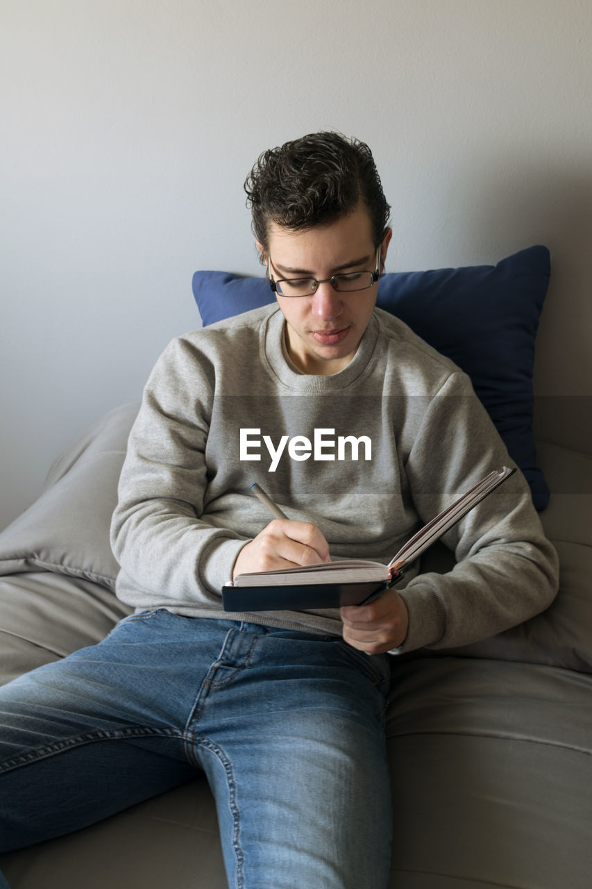 Man sitting on the bed writing on a notebook