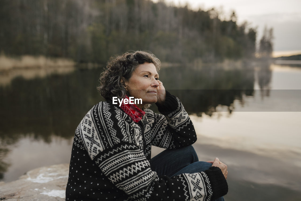 Caucasian female hiker contemplating while sitting by lake