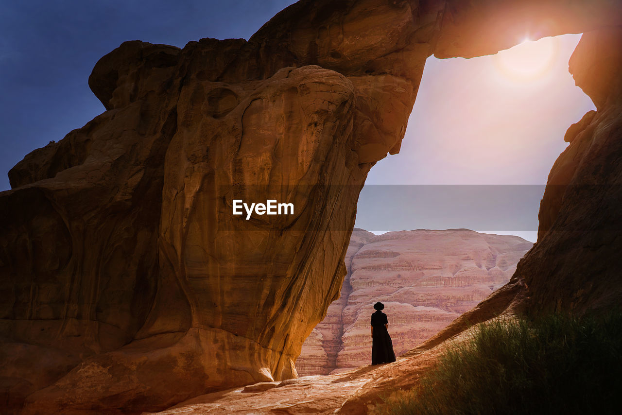 Rear view of woman standing on rock against mountain