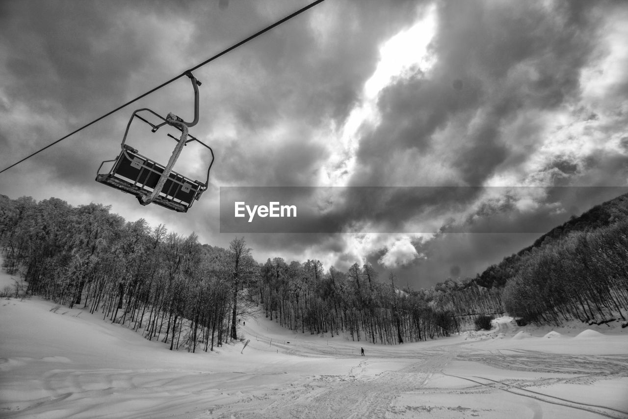 Ski lift over snowcapped mountains against sky