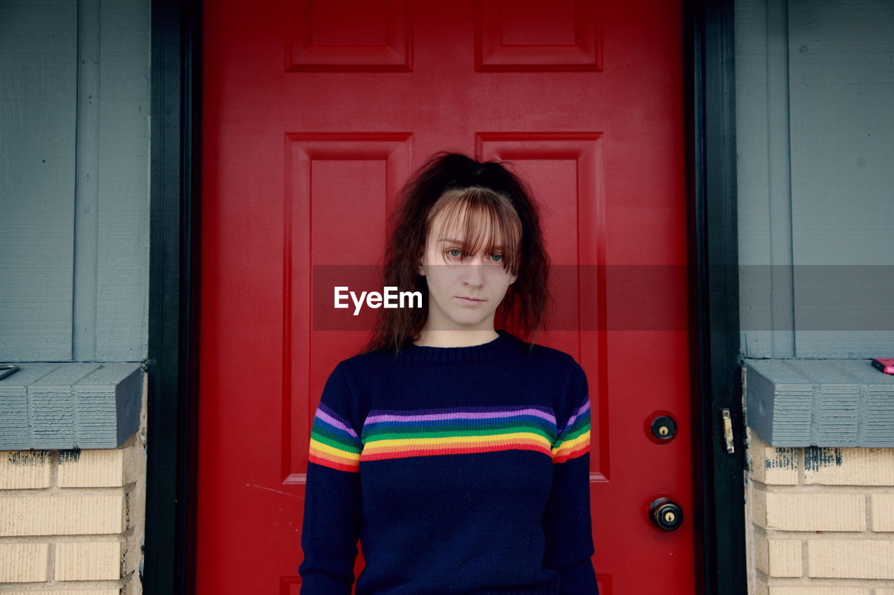 Portrait of teenage girl standing by red door