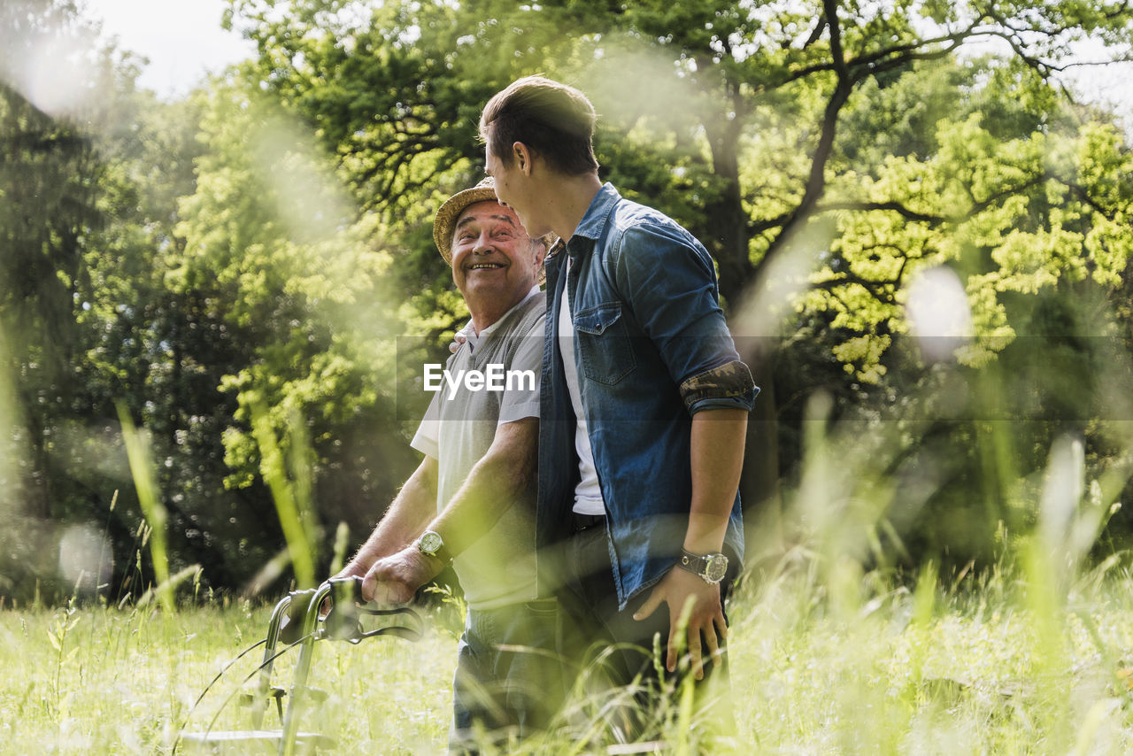 Happy grandfather walking with his grandson in nature