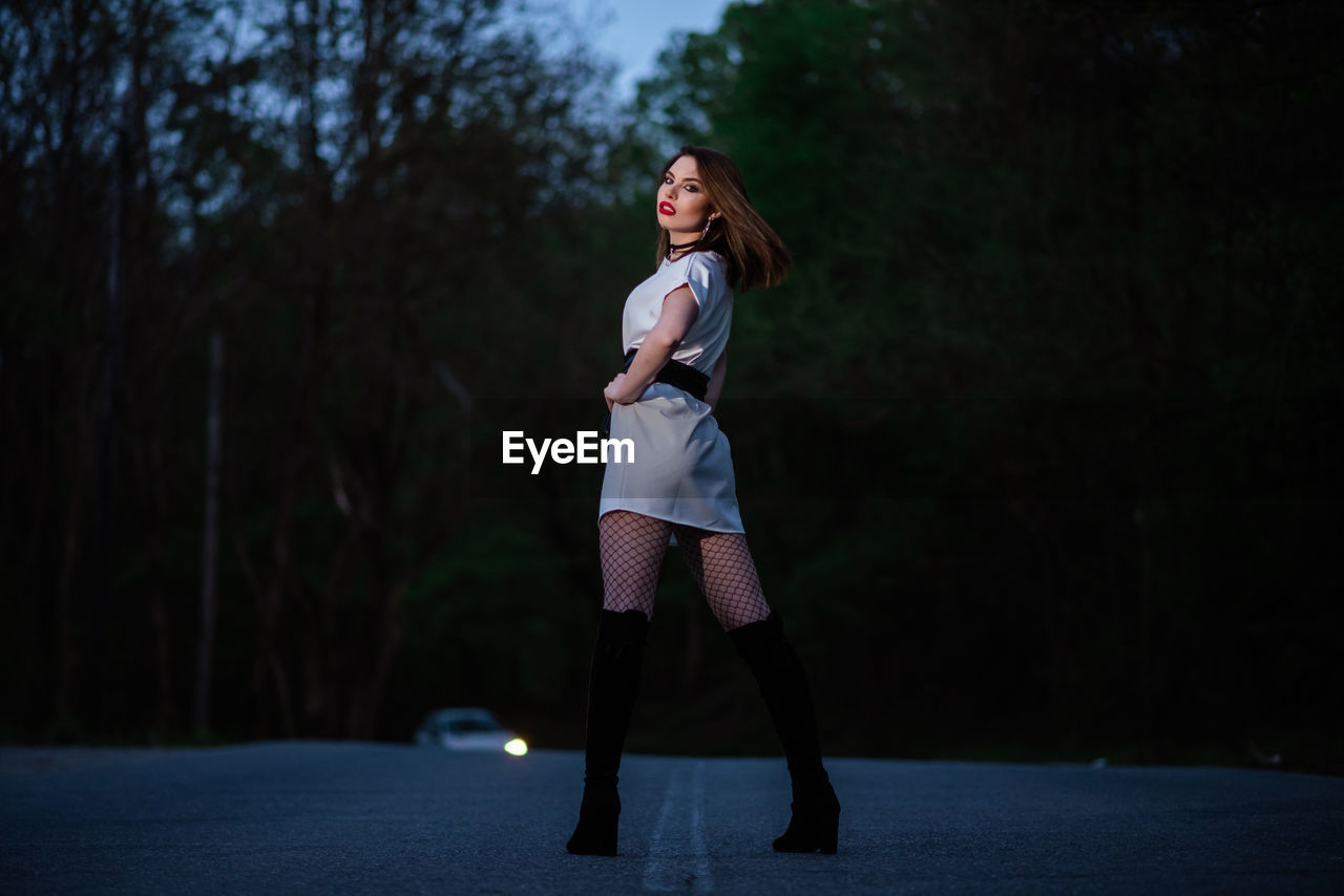 Full length of young woman standing against trees