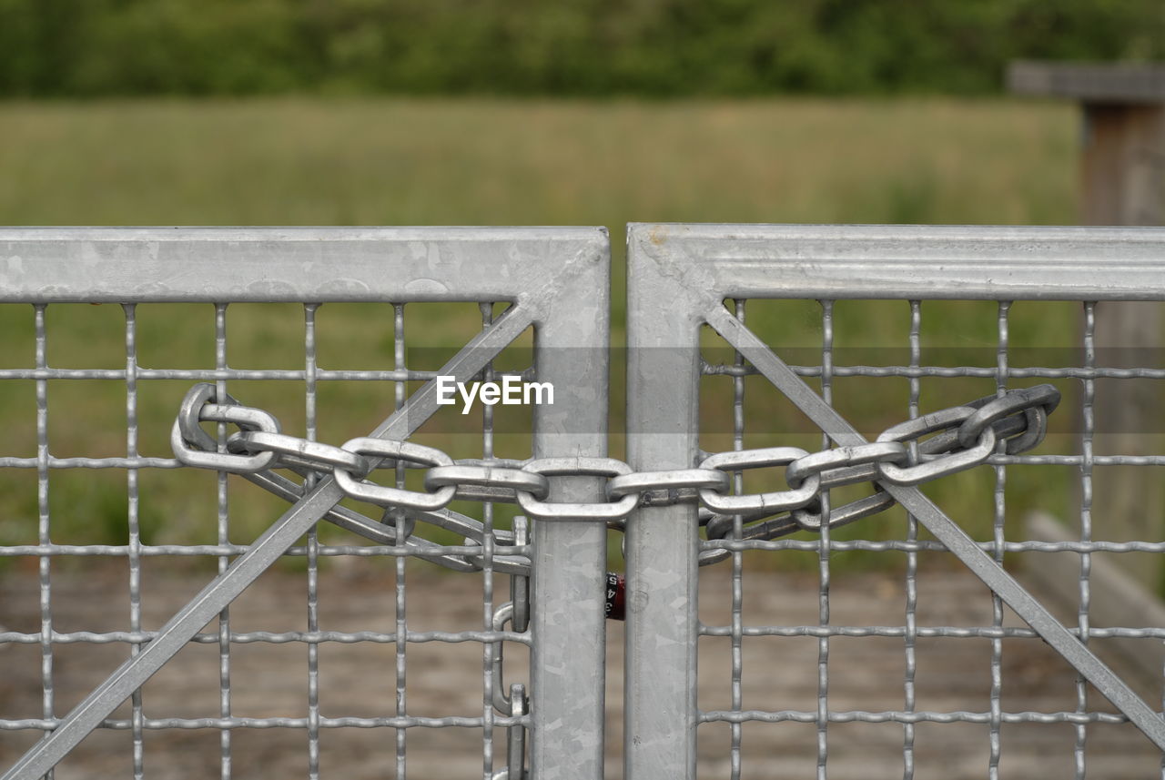 Close-up of metal fence, closed with a chain