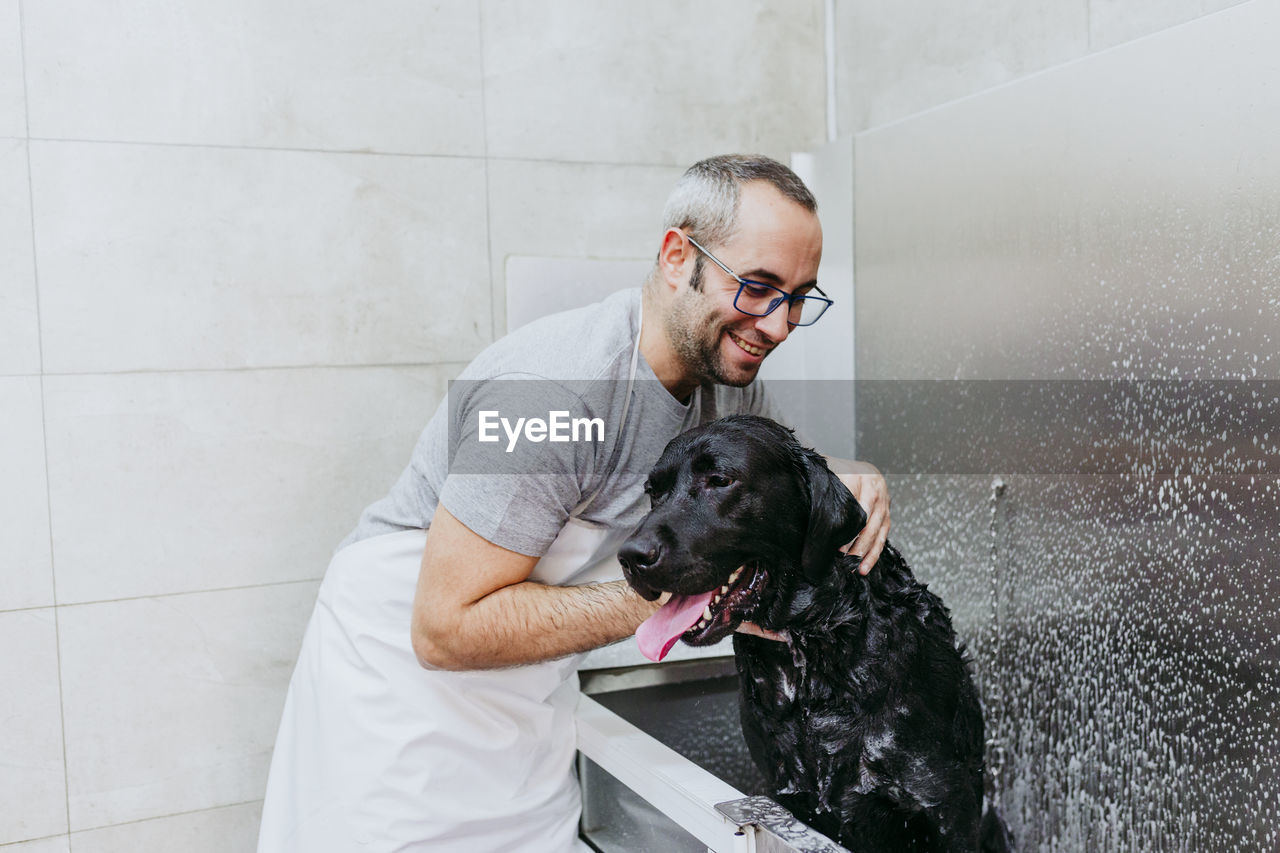 Man cleaning dog with water