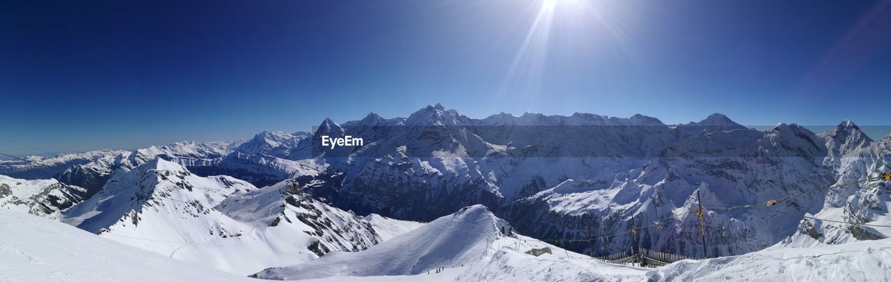 Panoramic view of snowcapped mountains against clear blue sky