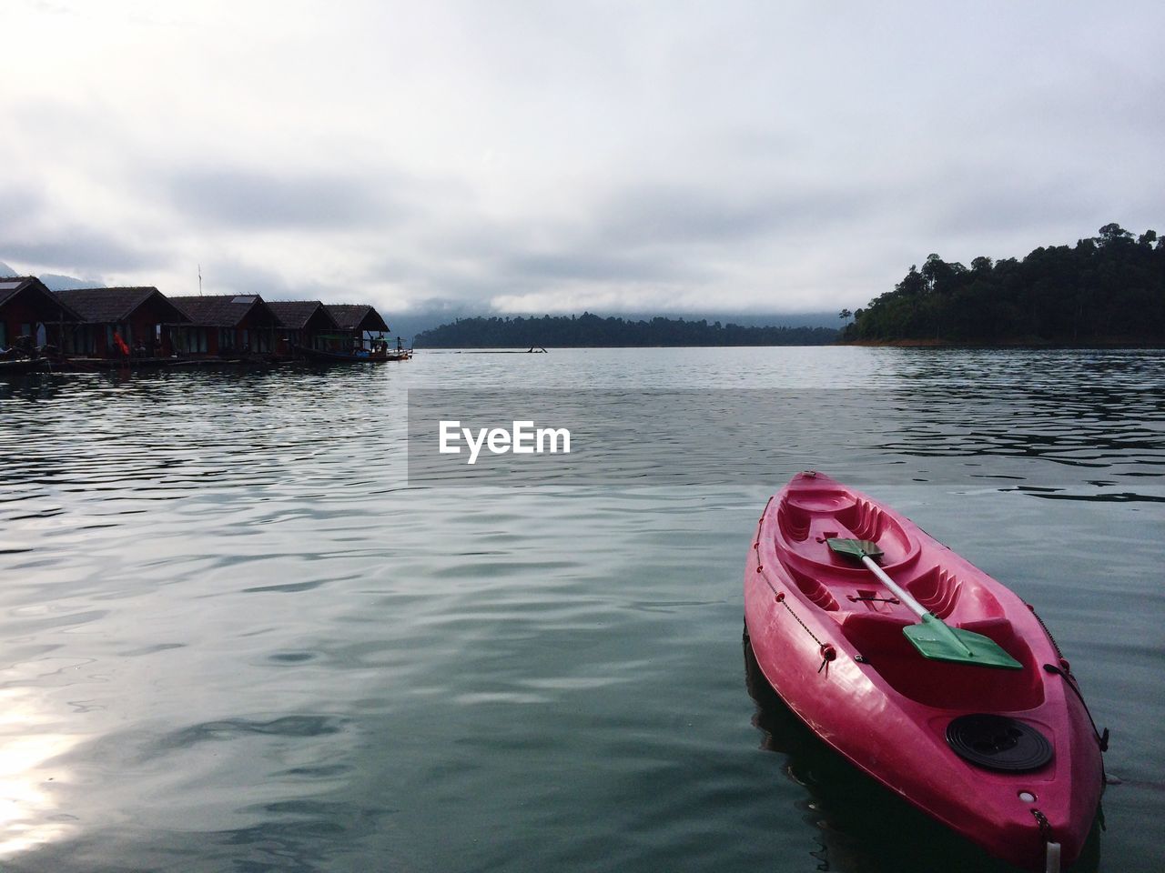 Empty kayak moored on river against sky