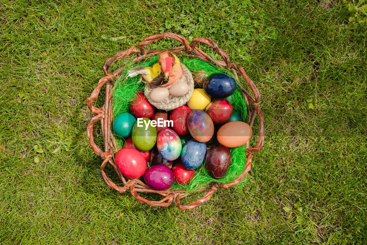 HIGH ANGLE VIEW OF MULTI COLORED EGGS IN WICKER BASKET