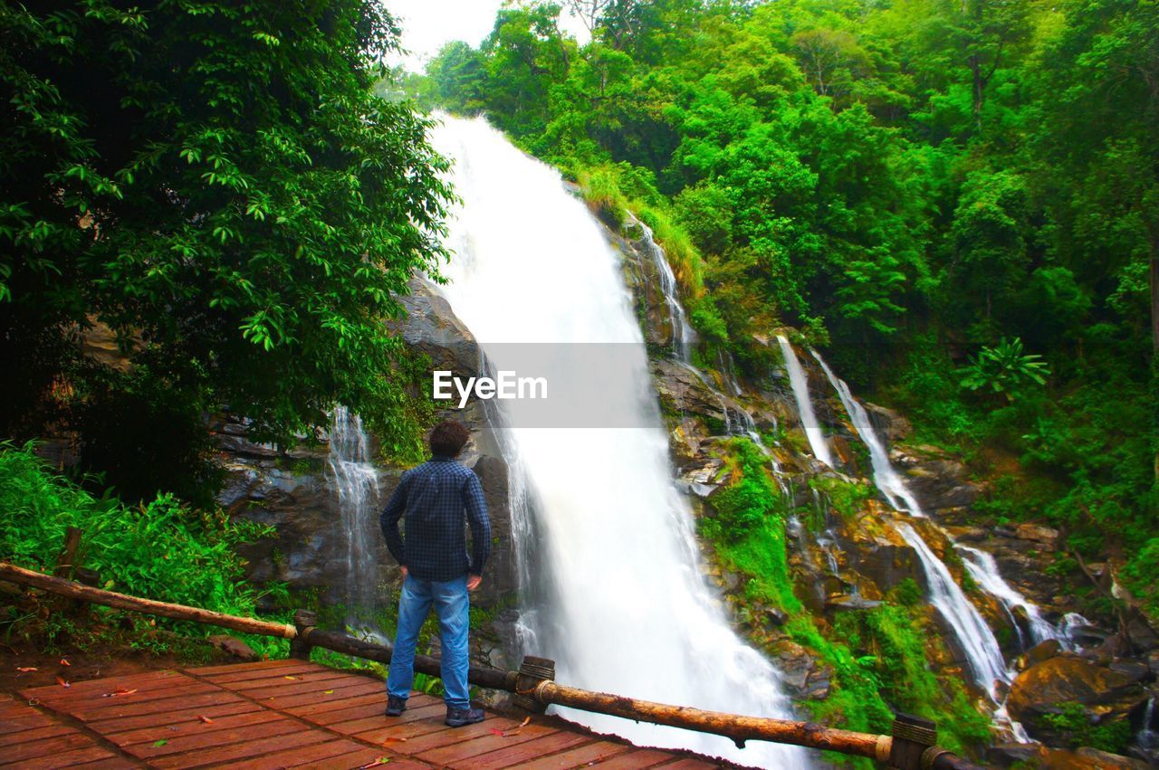 Rear view of man watching waterfall