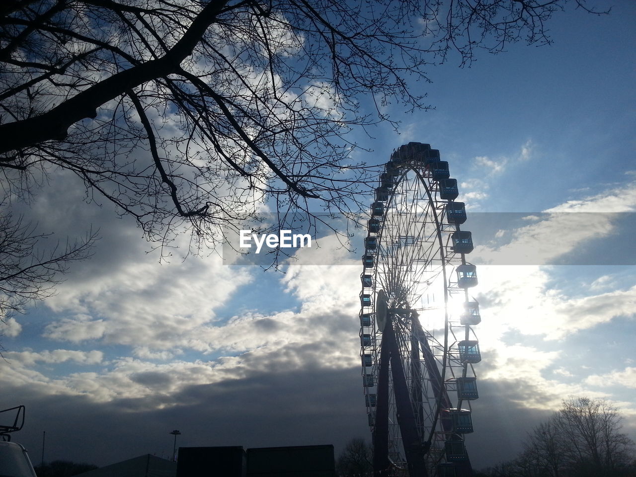 Low angle view of ferris wheel against clouds