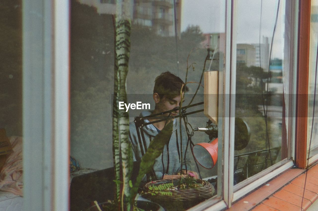 Man playing piano at home seen through glass