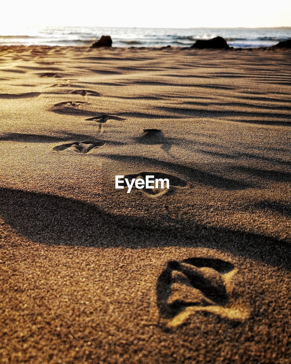 Footprints on sand at beach against sky