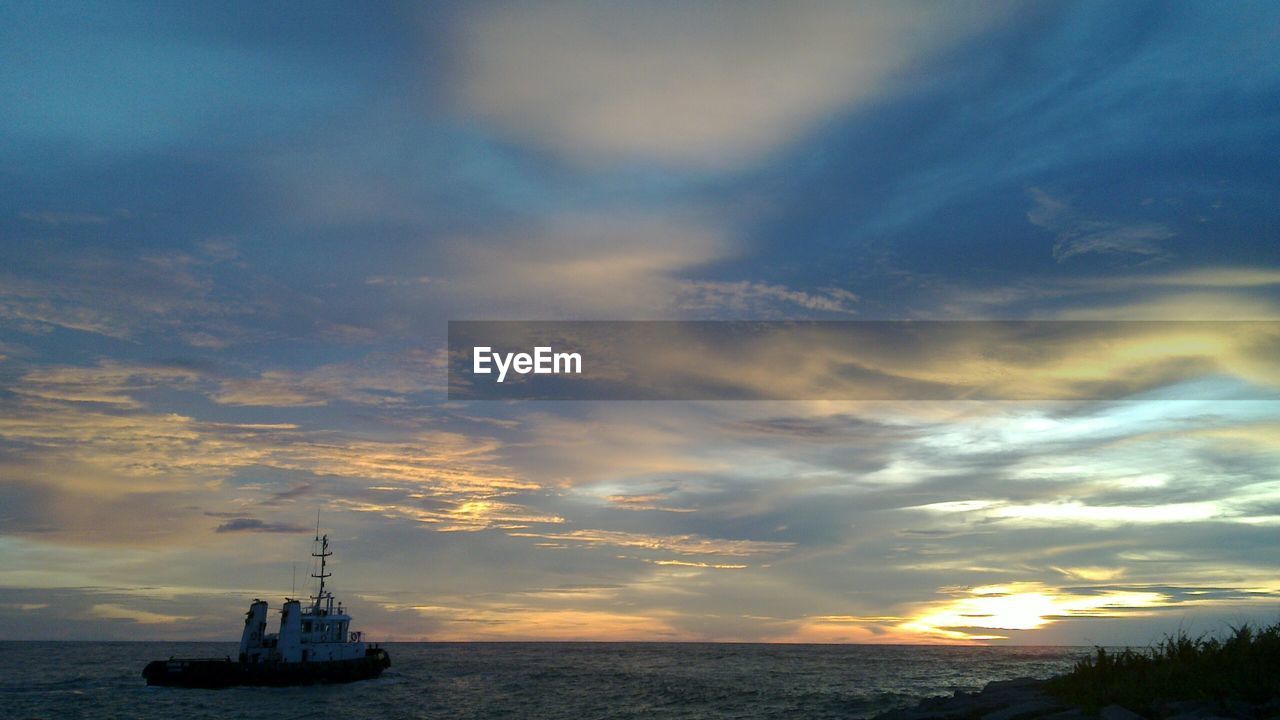 VIEW OF BOATS IN SEA AGAINST CLOUDY SKY