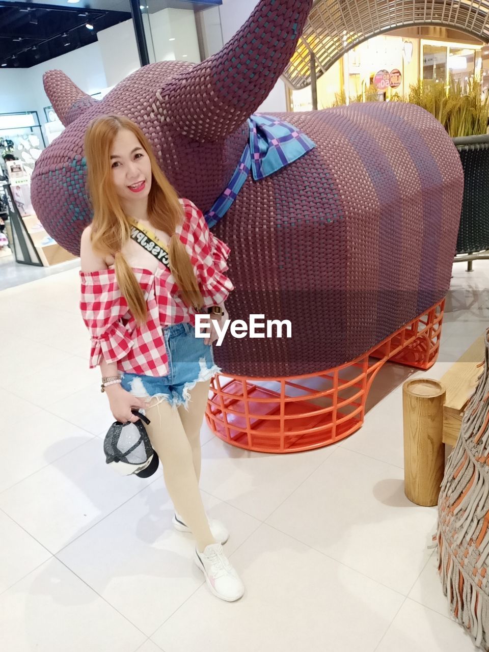 women, one person, full length, clothing, adult, hat, happiness, smiling, young adult, fashion, fashion accessory, casual clothing, long hair, portrait, emotion, lifestyles, footwear, shopping, blond hair, leisure activity, hairstyle, female, architecture, cheerful, retail, bag, enjoyment, looking at camera, standing, indoors, day, holding, front view, checked pattern, consumerism, person