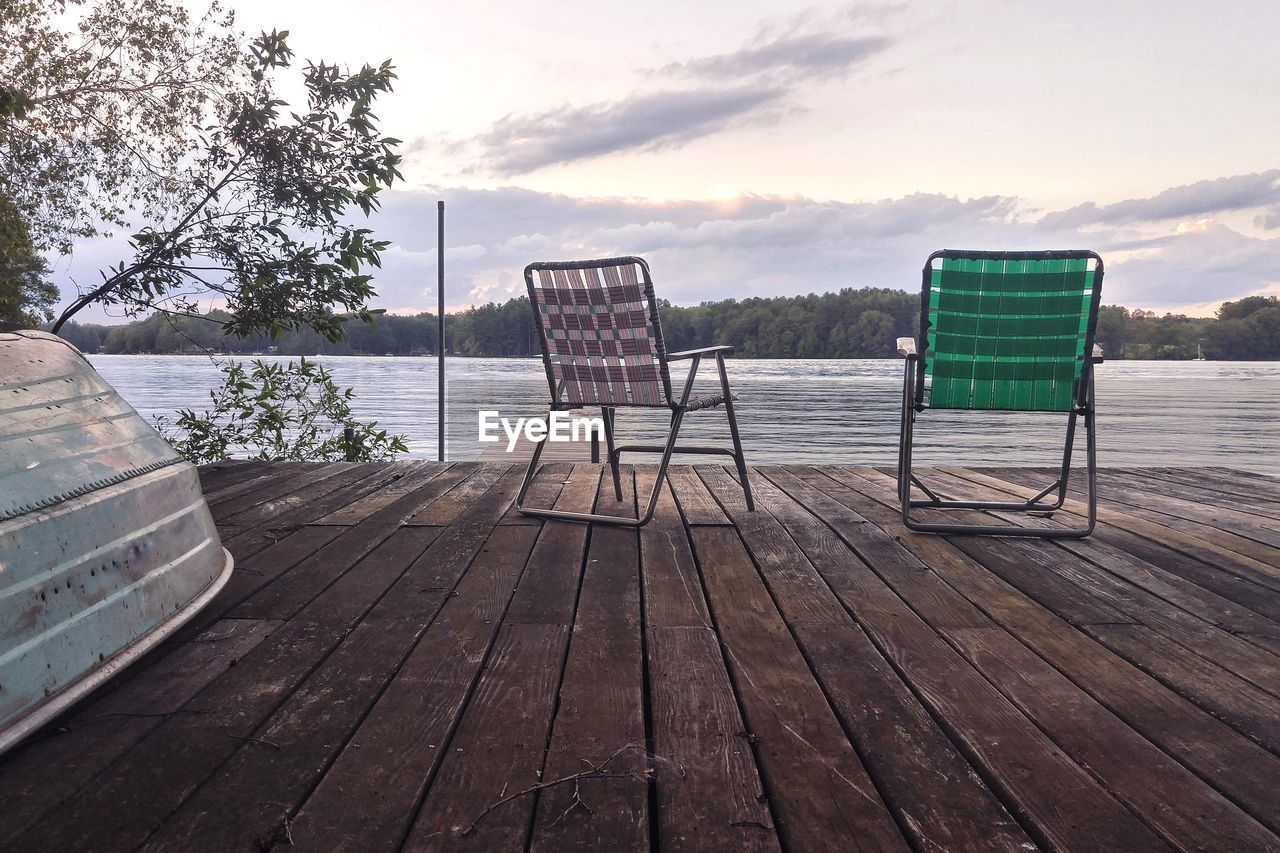 EMPTY CHAIR ON SEA SHORE AGAINST SKY