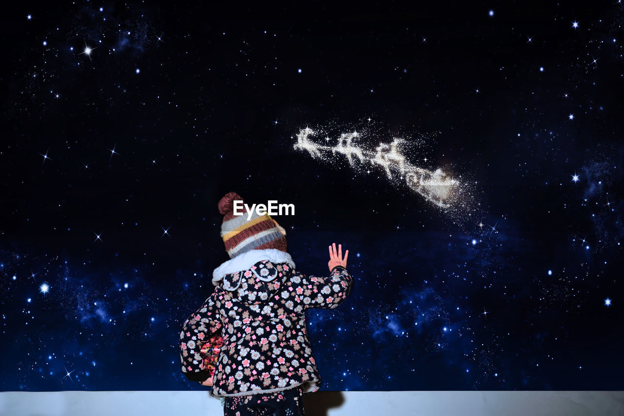 Digital composite image of girl standing against sky at night 