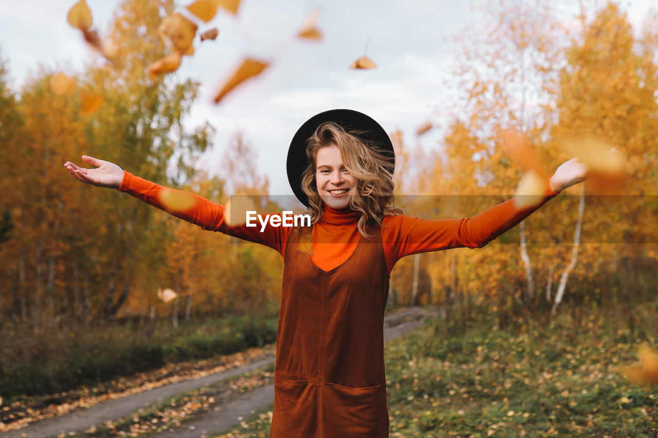 A pretty girl enjoys solitude drinks coffee walks in the autumn forest in nature in fall