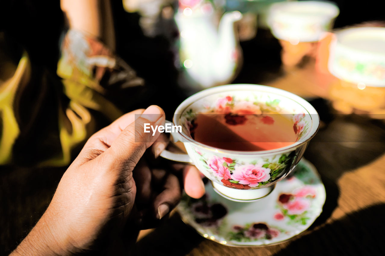 Cropped hand having tea in sunny day