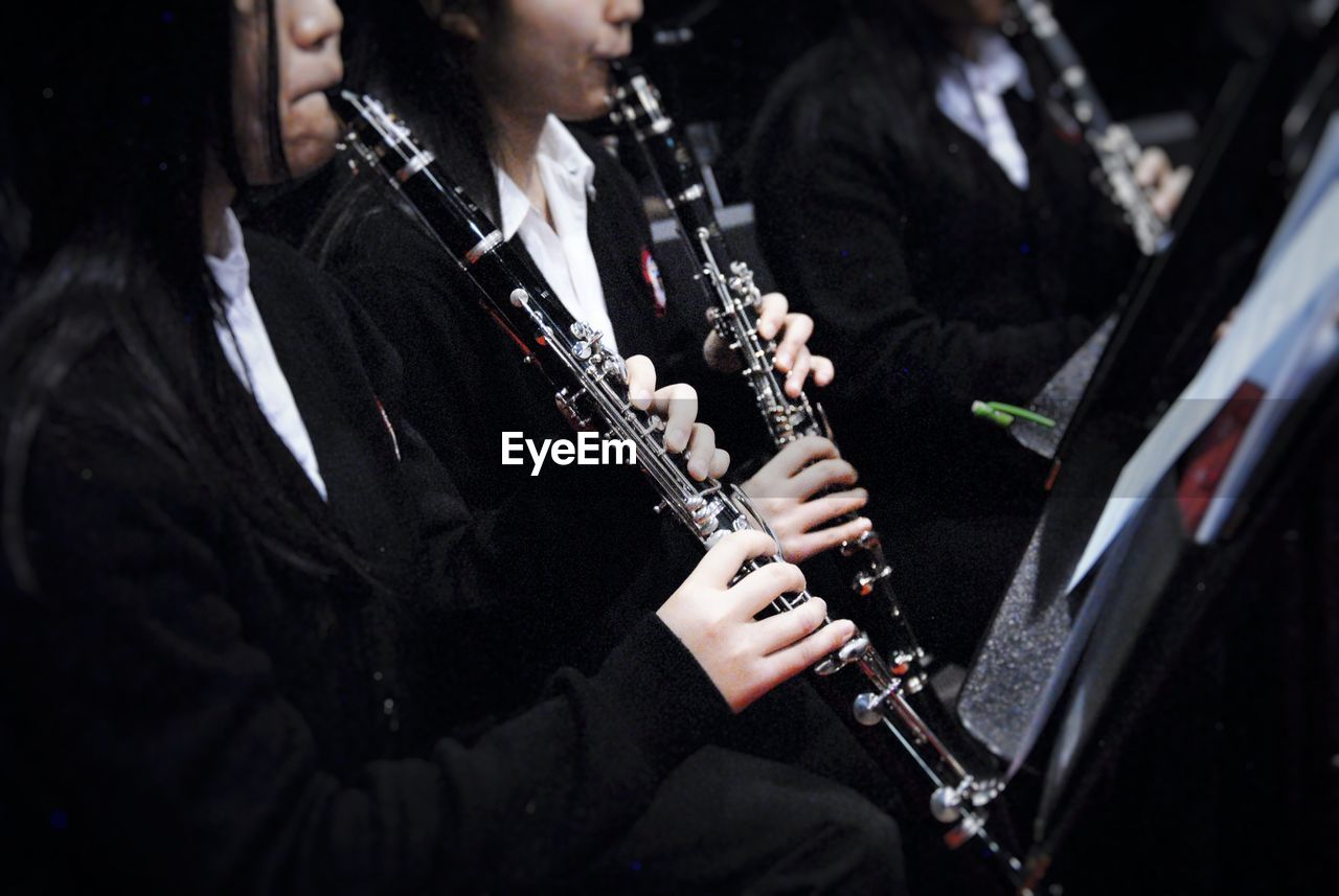 Midsection of women playing clarinet