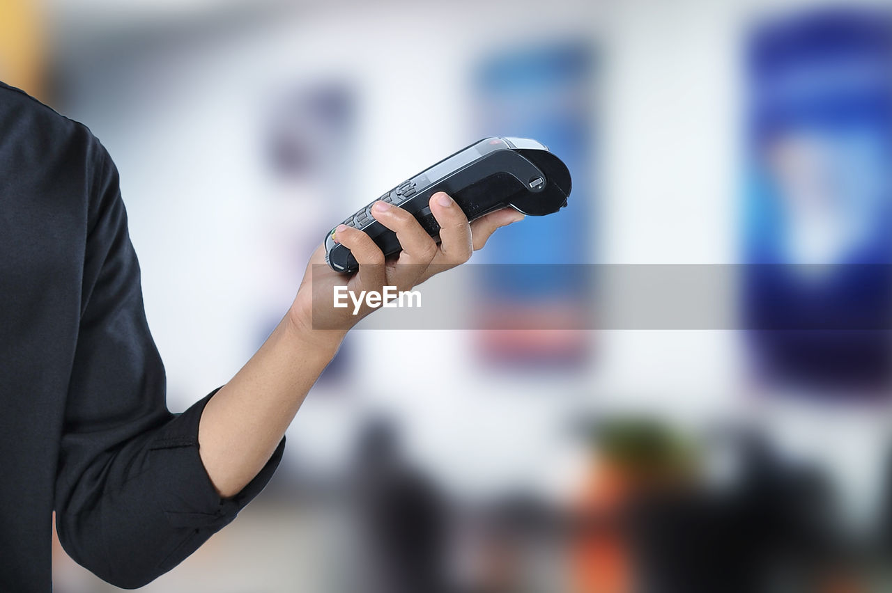 Young asian student holding an electronic data capture (edc) machine over beautiful blur background