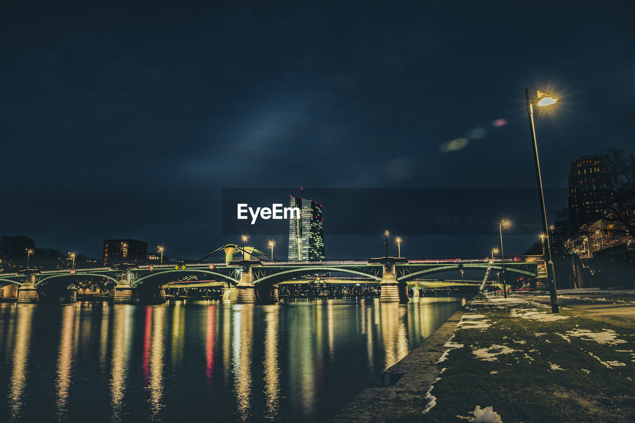 Illuminated bridge over river at night