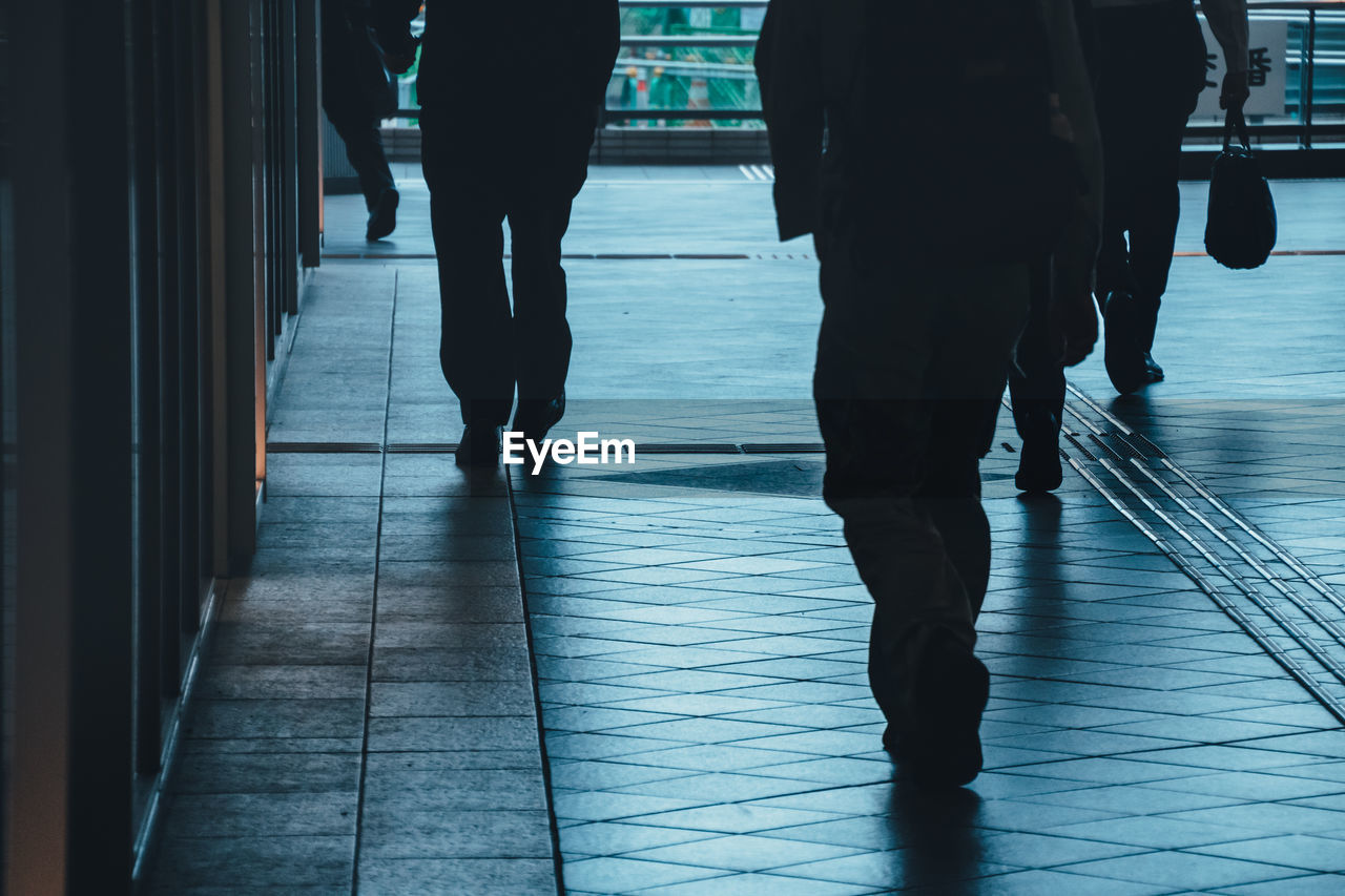 Low section of people walking on tiled floor