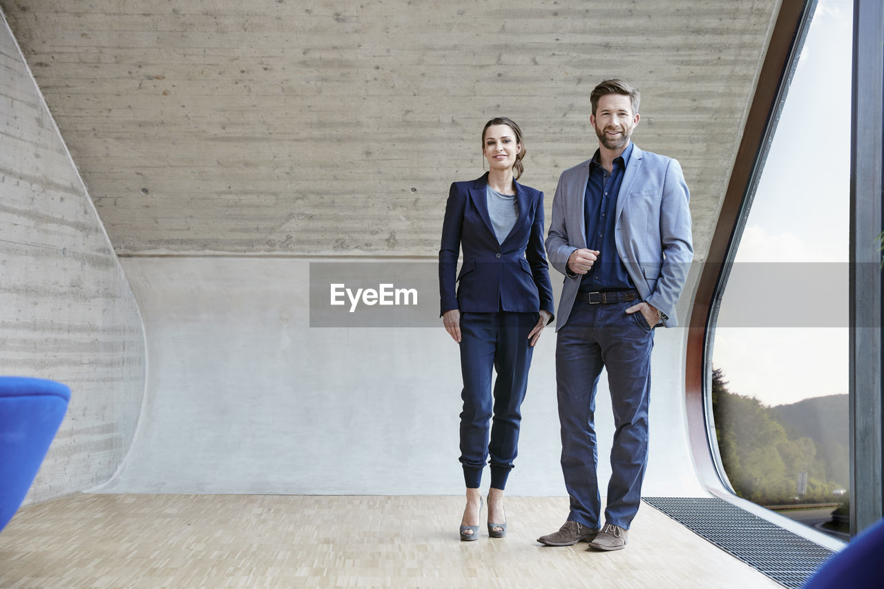 Portrait of smiling man and woman standing in attic office