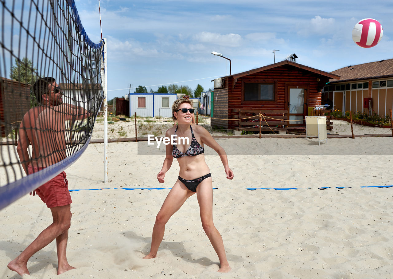 Full length of friends playing volleyball at beach