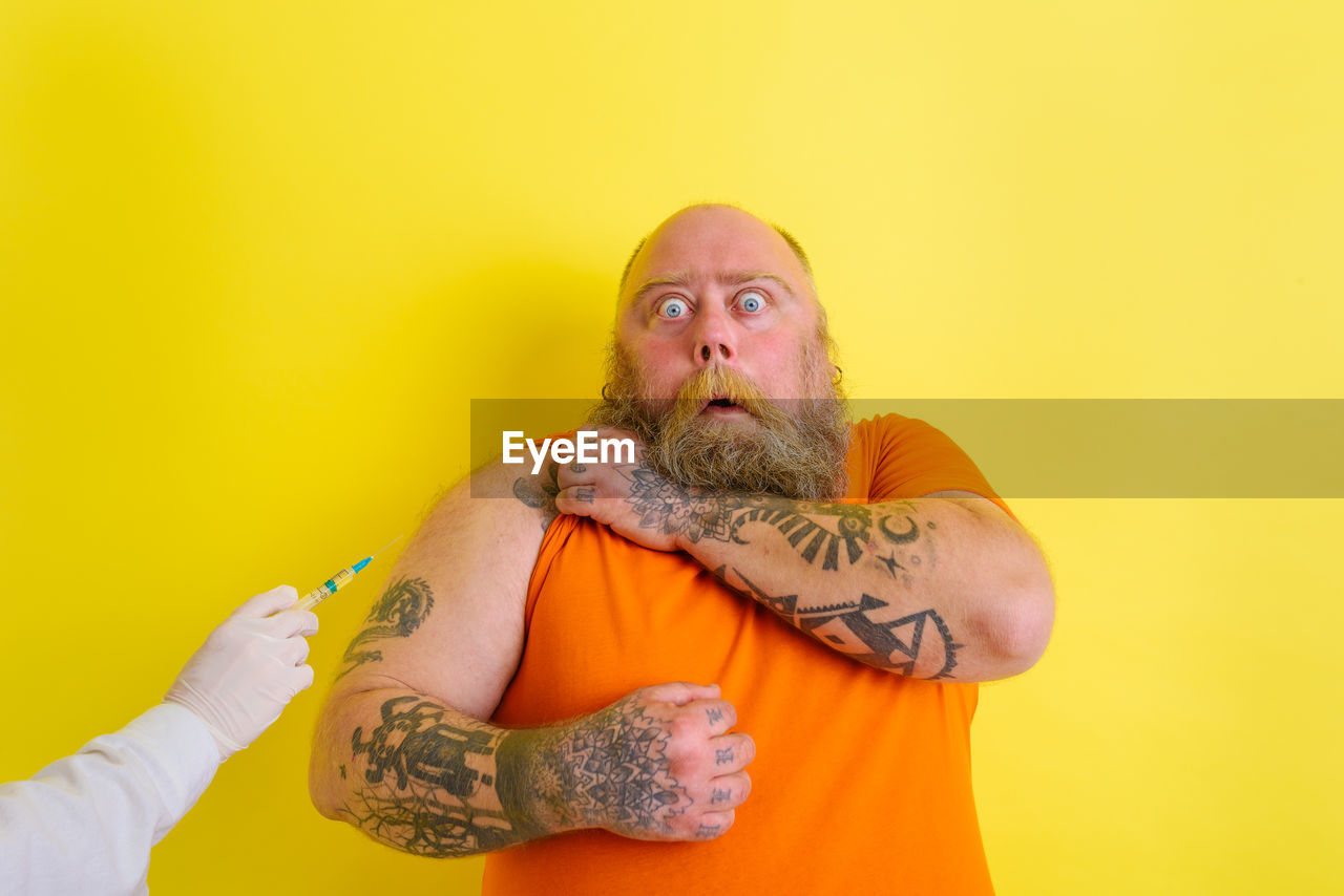 Portrait of man wearing mask against yellow background