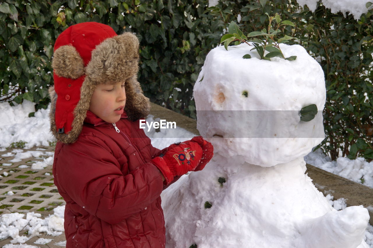 Cute boy making snowman outdoors