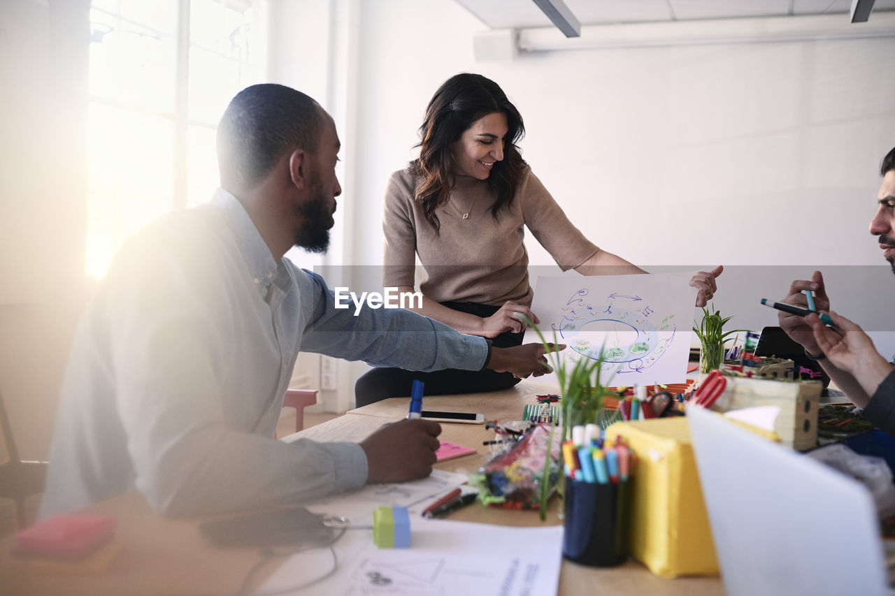 Multi-ethnic male and female engineers discussing over diagram at table during meeting in office