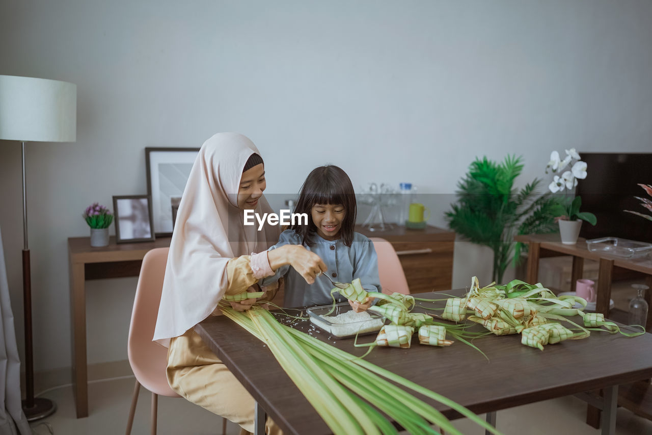 portrait of smiling woman with vegetables on table at home