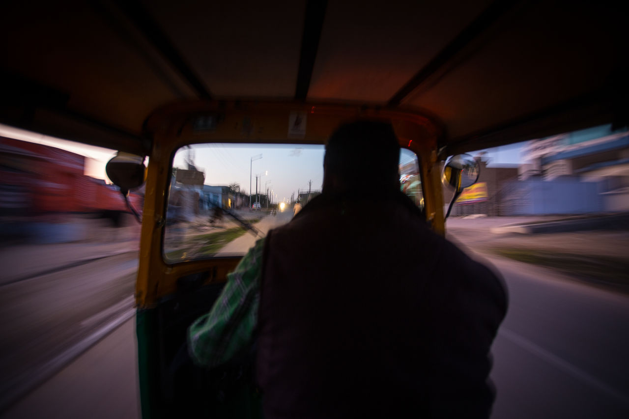 REAR VIEW OF MAN TRAVELING IN CITY