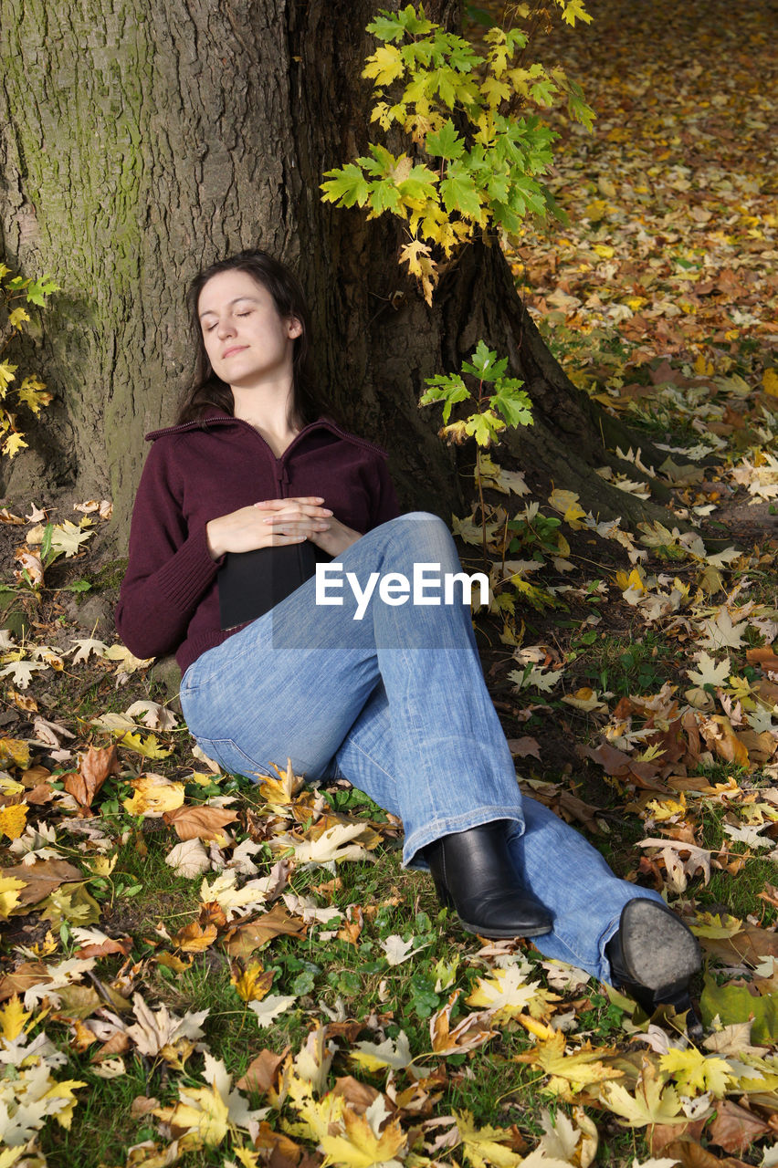 Portrait of young woman relaxing on field during autumn at herrenhausen gardens