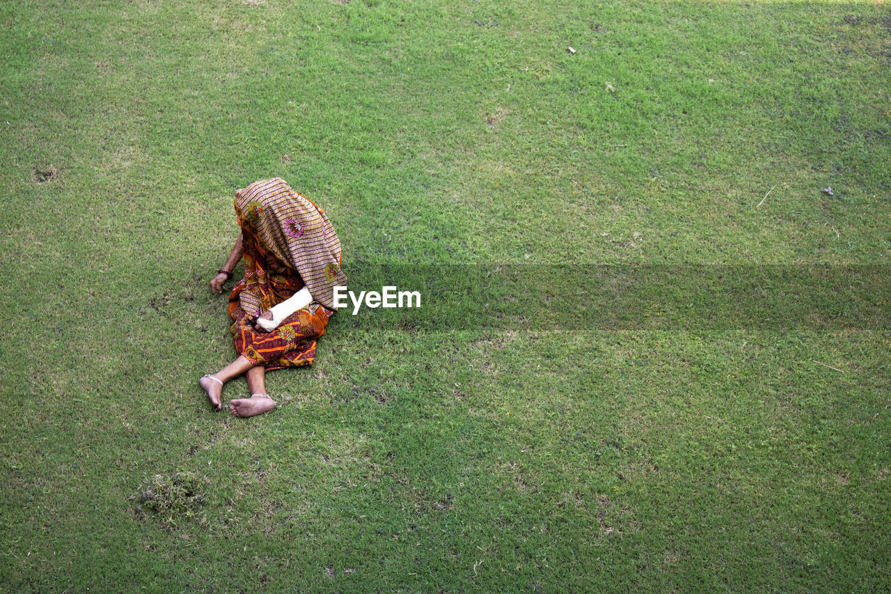 Woman weeding grass by hand - while one hand is injured