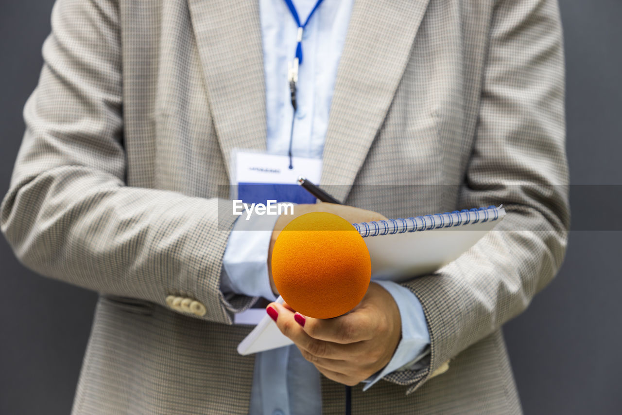 Journalist or reporter at media event, holding microphone, writing notes. journalism concept.