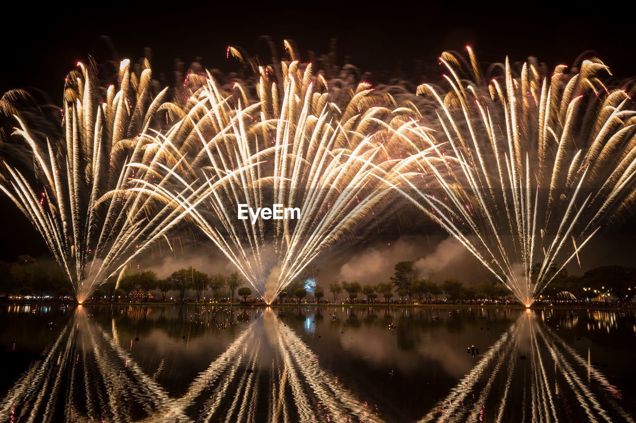 PANORAMIC VIEW OF FIREWORK DISPLAY OVER LAKE