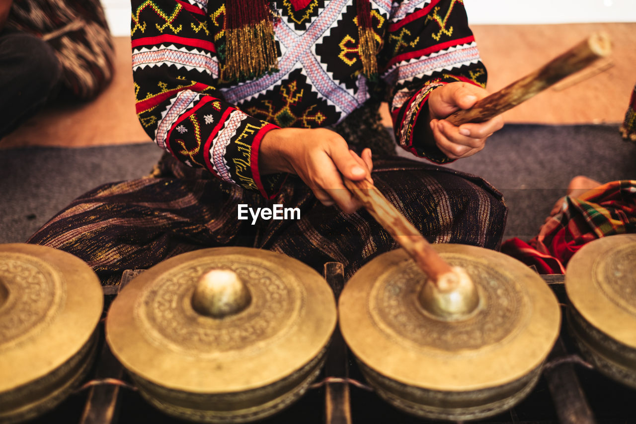 Midsection of woman playing traditional musical equipment