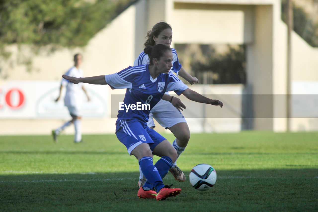 REAR VIEW OF GIRL PLAYING WITH SOCCER BALL ON GRASS