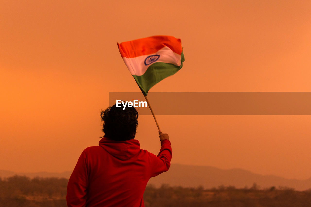 Rear view of man holding indian flag against clear sky