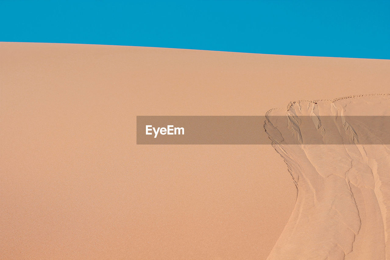 Sand dunes in desert against clear sky