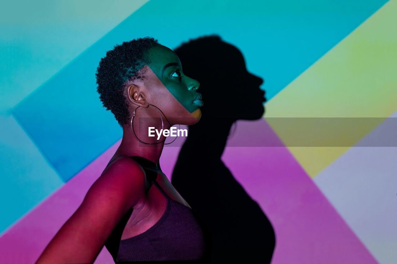 African american female with trendy earrings pointing at looking at camera against brown background